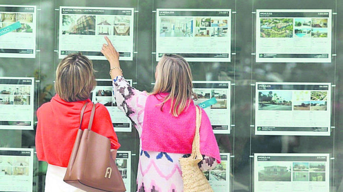 Dos personas consultan los anuncios de una inmobiliaria